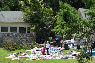 A woman sorts through clothing and campers' belongings outside cabins at Camp Mystic on July 8